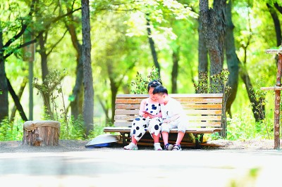     吉林省长春市以“绿色共享”理念为市民提供绿色公共产品。图为小朋友在南湖公园的长椅上玩耍。    新华社发